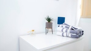 A white desk with a small potted plant, a glass bottle, and folded towels. - Large Shoreditch, Hoxton 3-Bed Garden Flat (London)