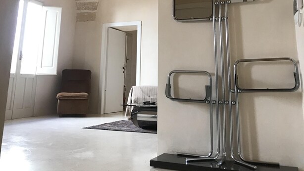 En rummelig stue med hvælvet loft, stenvæg og et stort spejl.