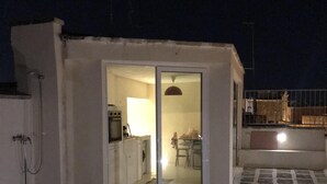 En lille, lukket patio med flisegulv og en glasdør ind til et indre rum.