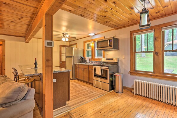 Una cocina con pisos de madera, un refrigerador, microondas y un ventanal con vistas al exterior.