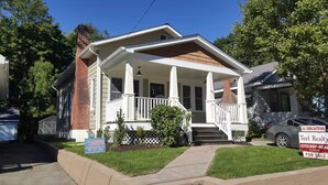 A two-story house with a front porch, brick chimney, and a lawn. - Very Welcoming (East Stroudsburg)