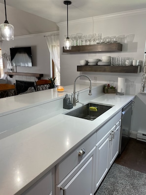 A modern kitchen with a large island, stainless steel appliances, and a built-in dishwasher.