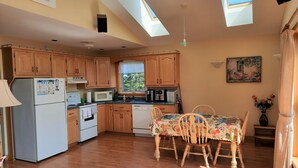 Una cocina con armarios de madera, una mesa de comedor con mantel floral y un cuadro en la pared.