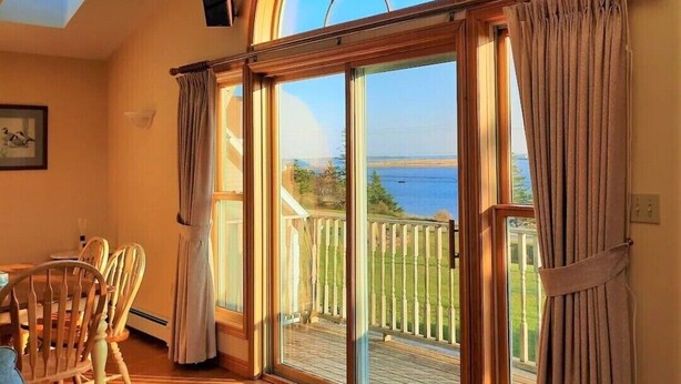 Una habitación con un amplio ventanal corredizo que da a una terraza con vistas al mar.