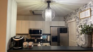A kitchen with a stainless steel refrigerator, a microwave, and a kettle on the counter. There is a chandelier hanging from the ceiling. - Momo's sweet home 2BR/2BA (Dallas)