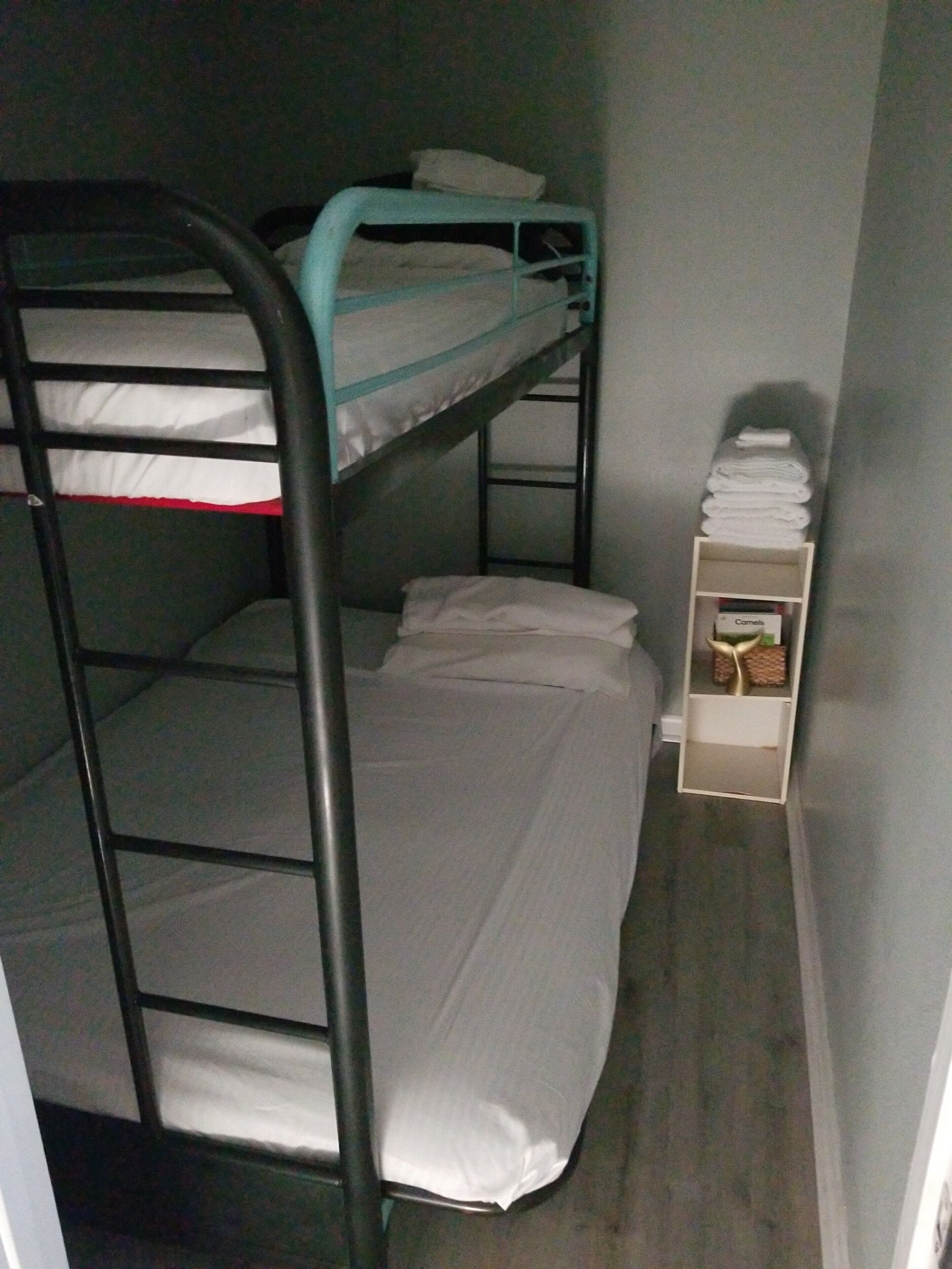 A bunk bed room with a small shelf holding towels and a box labeled "Camels".