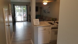 A kitchen with white cabinets, a stove, and a sign that reads "Sandy toes & Sally kisses". - 6 beds, 3 bedrooms, grill, small backyard and firepit, close to beach (Fort Walton Beach)