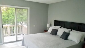 A bedroom with a large bed, a nightstand, a lamp, and a sliding glass door leading to a balcony. - 6 beds, 3 bedrooms, grill, small backyard and firepit, close to beach (Fort Walton Beach)