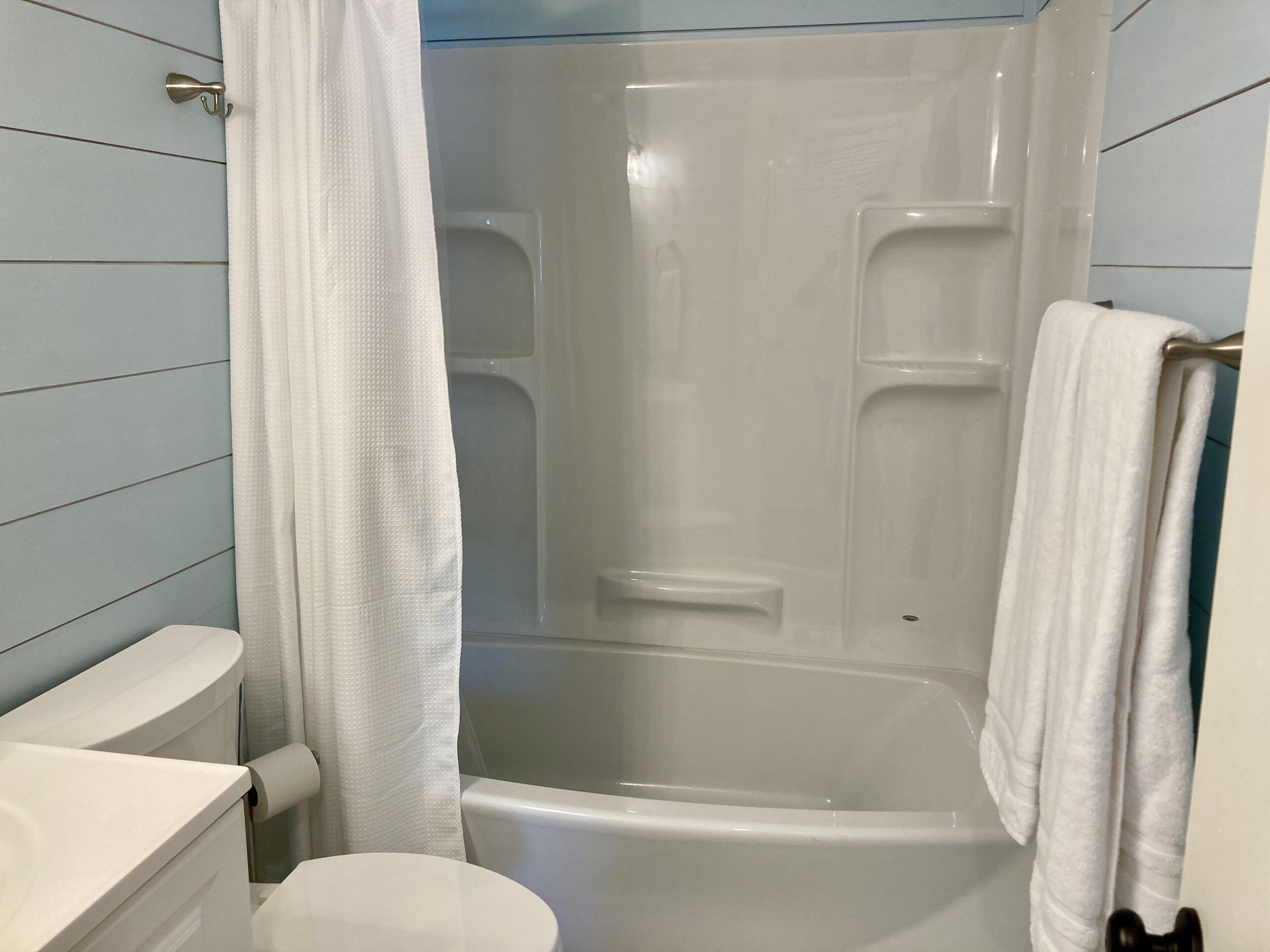 Un baño con bañera, inodoro y cortina de ducha.