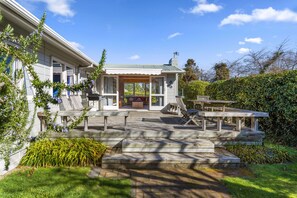 Ein Haus mit überdachter Terrasse, Sitzgelegenheiten im Freien und einem gepflegten Garten.