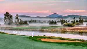 A golf course with a flagstick, water hazards, and a mountain in the background. - Walk to Village, Sharc Passes, Air Conditioning, King Bed, Bikes (Sunriver)