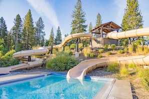A pool area with multiple slides and a wooden deck structure. - Walk to Village, Sharc Passes, Air Conditioning, King Bed, Bikes (Sunriver)
