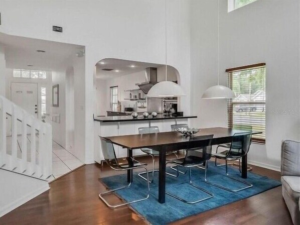 A modern kitchen with white cabinets, a central island, and pendant lighting.