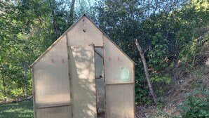 Eine kleine, einstöckige Gartenhütte mit einem Dreiecksdach und einer Tür.