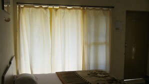 A room with a bed, curtains, and a door.