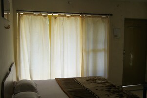 Una habitación con cama, cortinas y una puerta.