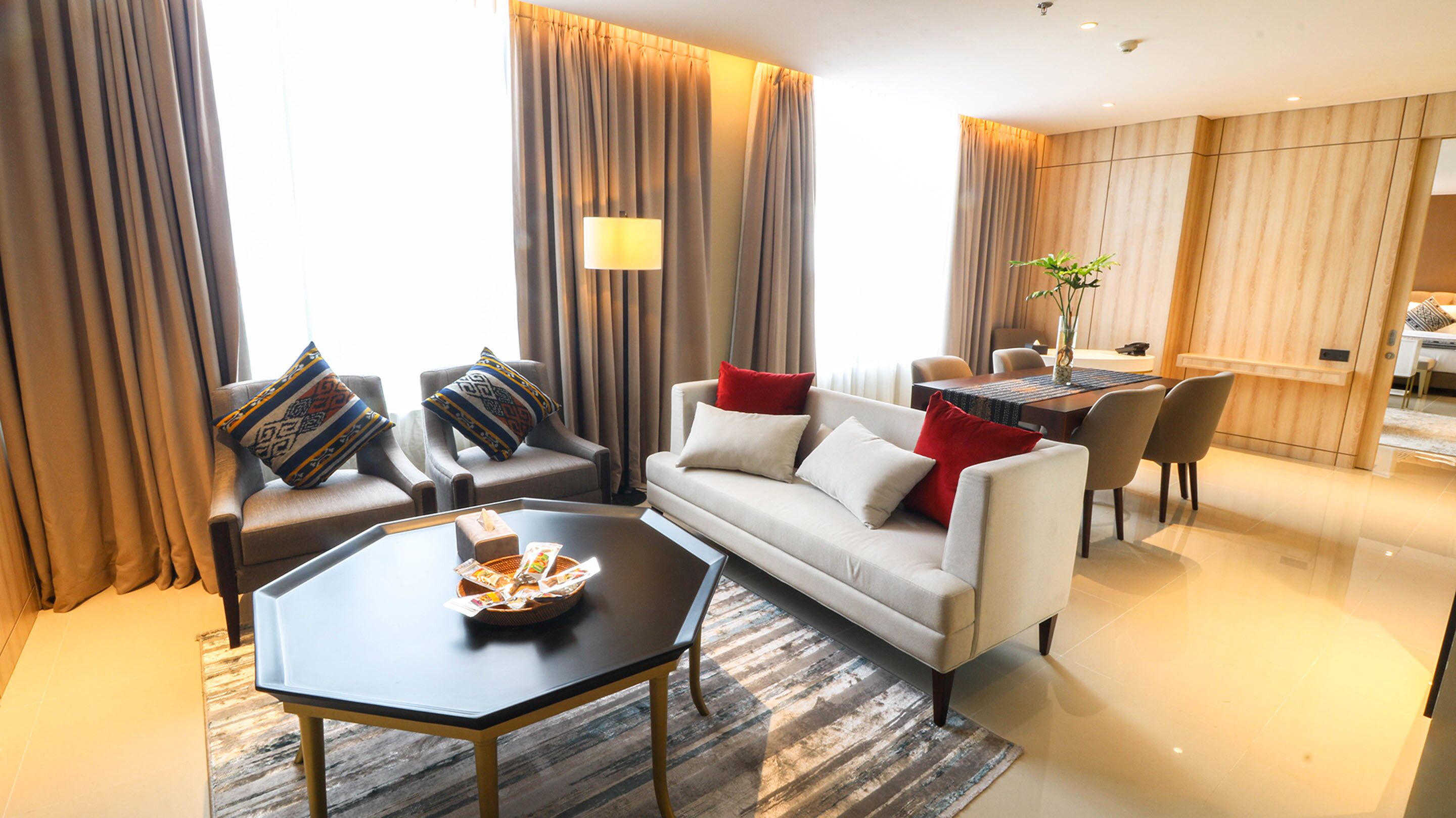 Una sala de estar moderna con un sofá, sillones, una mesa de centro y un comedor con una mesa y sillas.