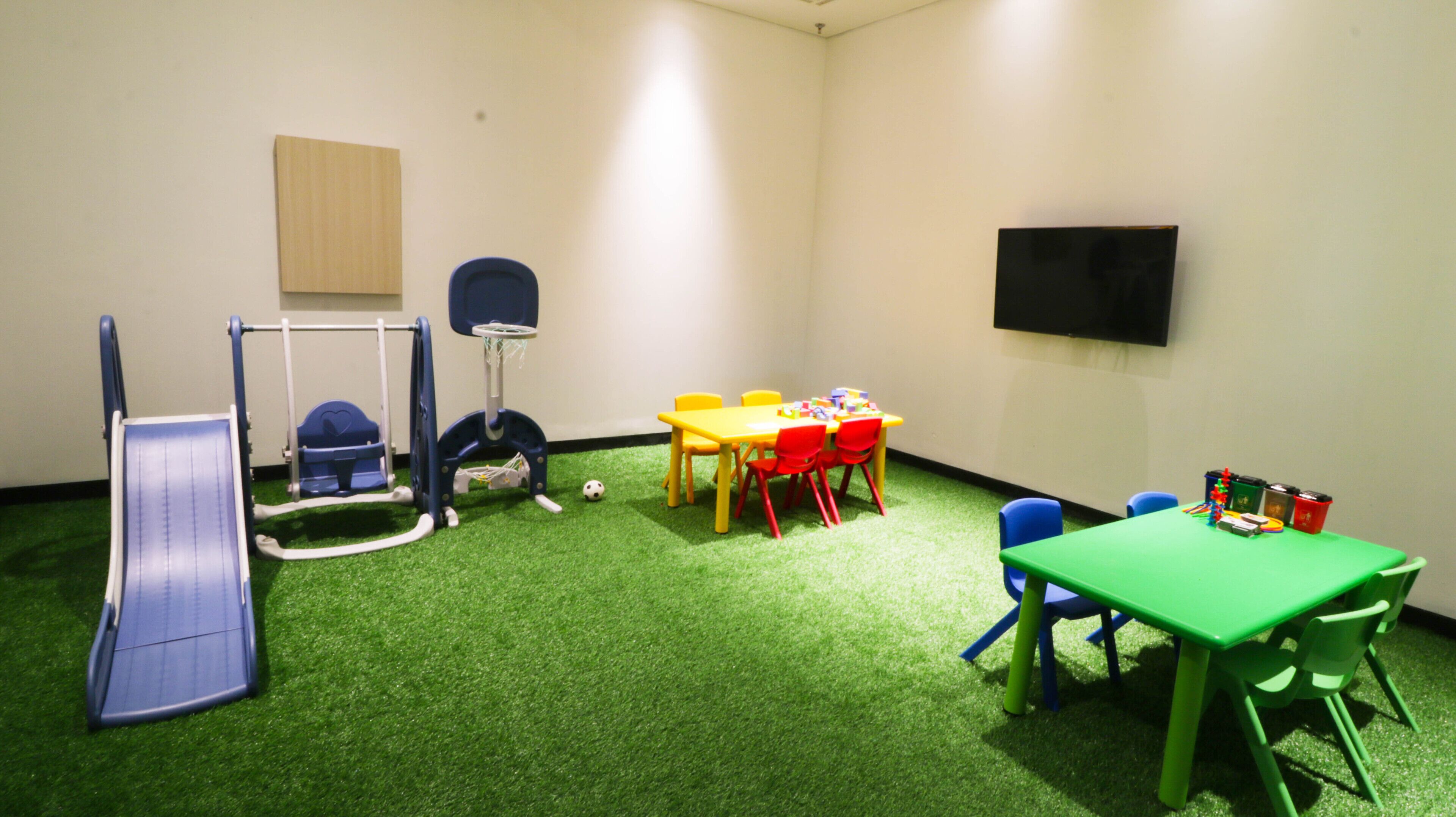 Sala de juegos con un tobogán, estructura de escalada y una mesa con sillas.