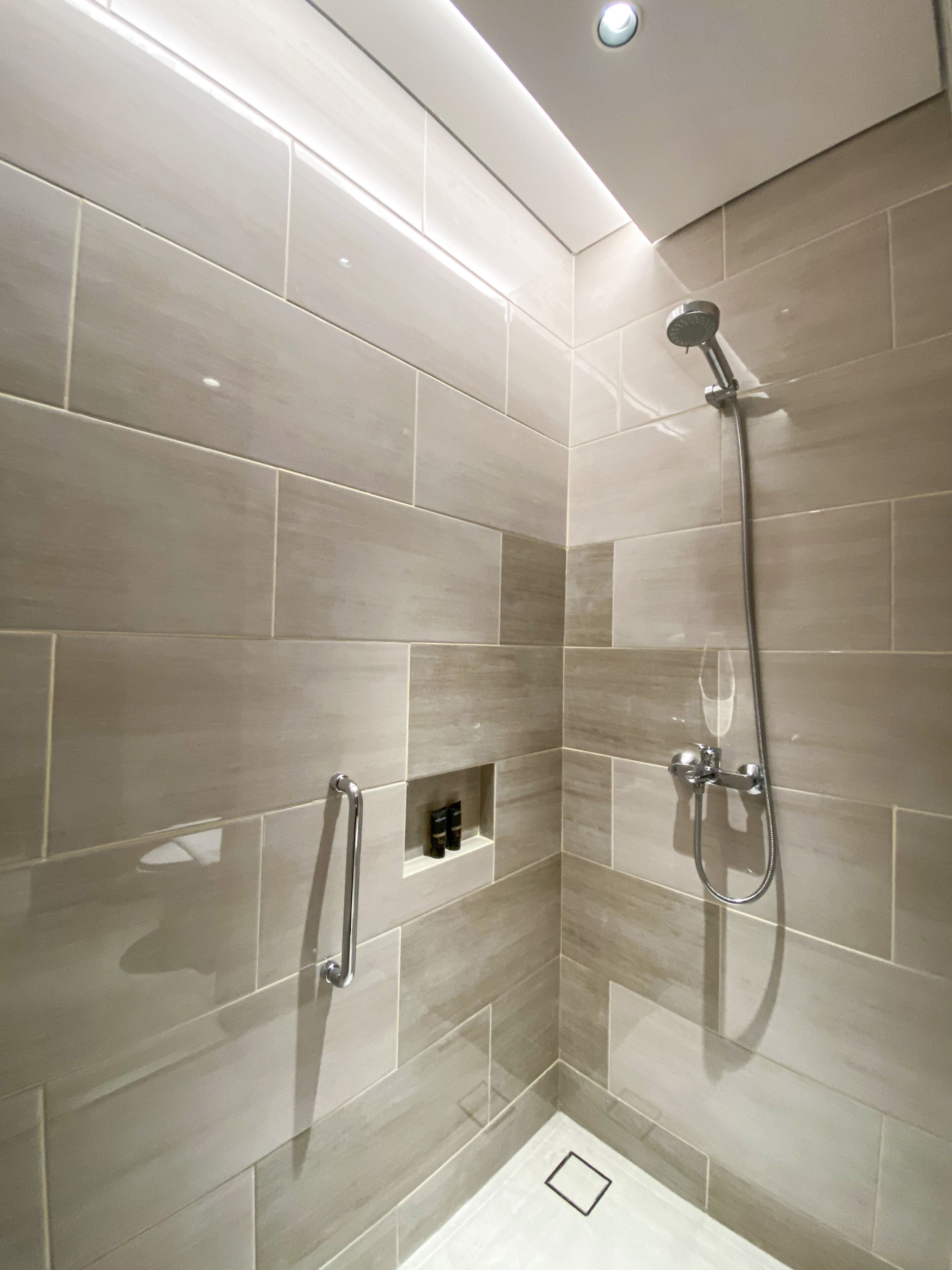 A modern shower area with a handheld showerhead and a wall-mounted faucet.