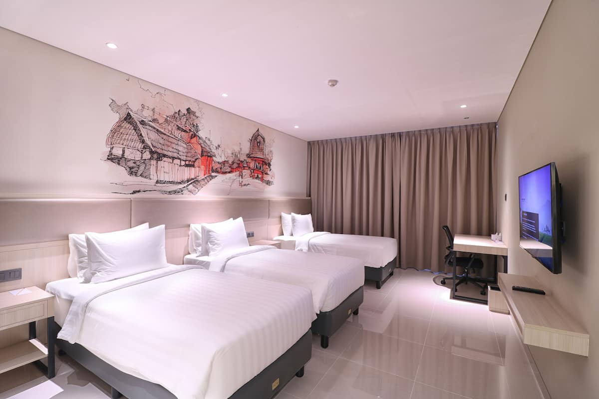 A hotel room with two beds, a desk, a chair, a TV, and a large wall mural.