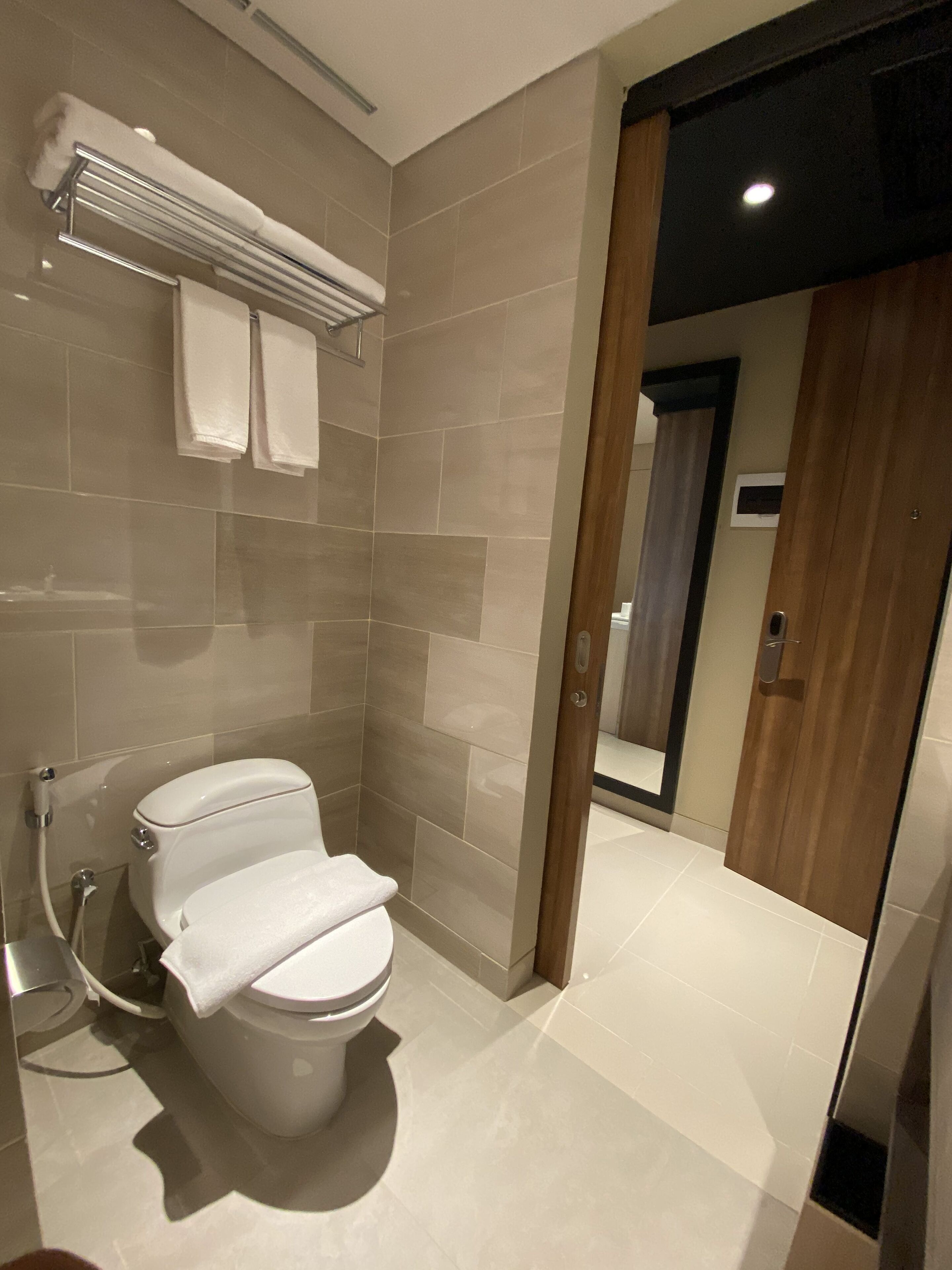 Un baño moderno con inodoro, toallero y zona de ducha.