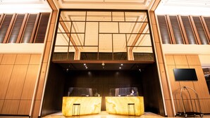 A lobby with a reception desk, a large digital screen, and a ceiling with a geometric pattern. - Prime Park Hotel & Convention Lombok (Mataram)