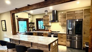 A modern kitchen with a central island, bar stools, stainless steel appliances, and wooden cabinetry. - Mt Baker Luxury Cabin • 2 King Beds • Hot Tub • Game Loft • Firepit (Deming)