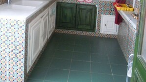 A compact kitchen with white cabinets, a microwave, a sink, and patterned backsplash tiles. - House With Garden Wala (El Djem)