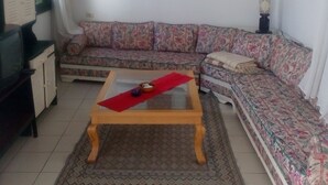 A living room with a sofa, a coffee table, a television, and artwork on the wall. - House With Garden Wala (El Djem)
