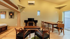 Un amplio espacio de estar con una mesa de comedor de madera, sillas, un sofá y un televisor.