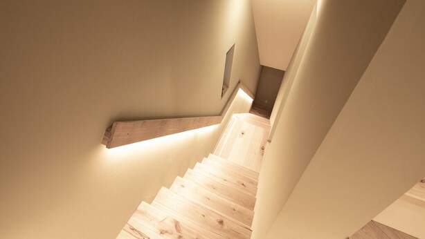 Una escalera con escalones de madera y una lámpara en la pared.