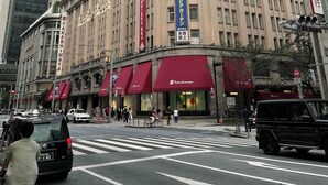 Un edificio histórico con varios comercios en la planta baja, incluyendo un restaurante con toldo rojo.