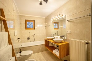 Une salle de bain moderne équipée d’une baignoire, de deux lavabos, de toilettes et d’une douche.