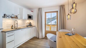 Een moderne keuken met witte kasten, een houten aanrecht en een raam met uitzicht op besneeuwde bergen.