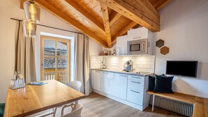 A modern kitchen with white cabinets, a wooden ceiling, a built-in microwave, and a TV mounted on the wall. - Apartment "Mountain Residence Kasern Nr 3" with Mountain View, Garden & Wi-Fi (Prettau)