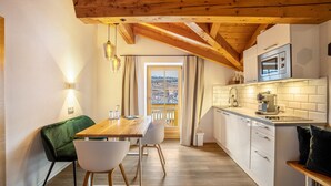 A kitchen with a wooden ceiling, white cabinets, a built-in oven, and a window with curtains. - Apartment "Mountain Residence Kasern Nr 3" with Mountain View, Garden & Wi-Fi (Prettau)