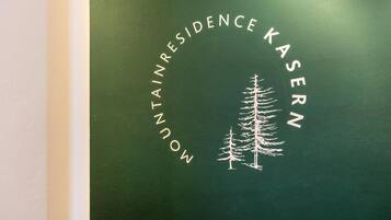 A green wall with the text 'MOUNTAIN RESIDENCE KASERN' and a white tree silhouette.