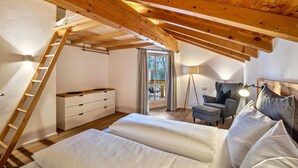A bedroom with a lofted sleeping area, wooden beams, a desk, chair, and a window with curtains. - Apartment "Mountain Residence Kasern Nr 4" with Mountain View, Balcony & Wi-Fi (Prettau)