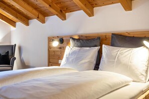 A bedroom with a wooden headboard, white bedding, and a wall-mounted light fixture.