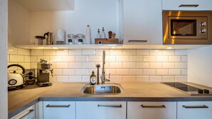 A modern kitchen with a stainless steel sink, a coffee maker, and a microwave. - Apartment "Mountain Residence Kasern Nr 4" with Mountain View, Balcony & Wi-Fi (Prettau)