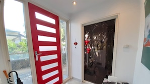 A modern entrance with a red door, a glass door, a bench, and a small table with a bag on it. - StayCentral - Fairfield 4Br Home (Fairfield)