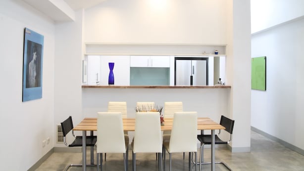 A modern dining area with a wooden table and white chairs, a kitchen with white cabinets and a stainless steel refrigerator, and a blue vase on the counter. - StayCentral - Fairfield 4Br Home (Fairfield)