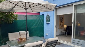 A patio with a glass table, two chairs, a striped umbrella, and a birdcage on a blue wall. - StayCentral - Fairfield 4Br Home (Fairfield)