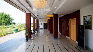 A hotel corridor with a chandelier, wooden doors, and a view of the outdoors.