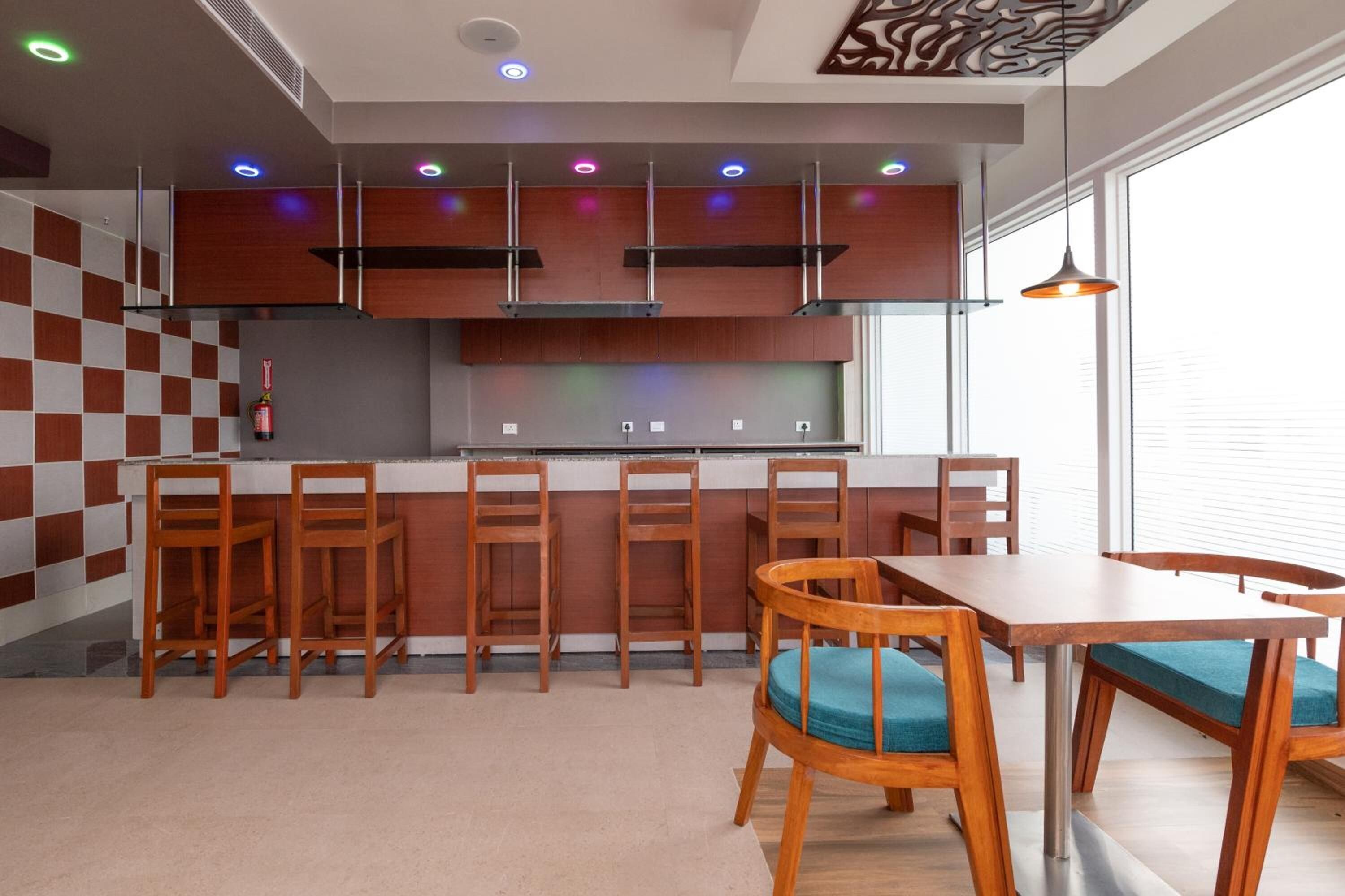 Una cocina moderna con armarios de madera, una isla central con taburetes y una zona de comedor con mesa y sillas.