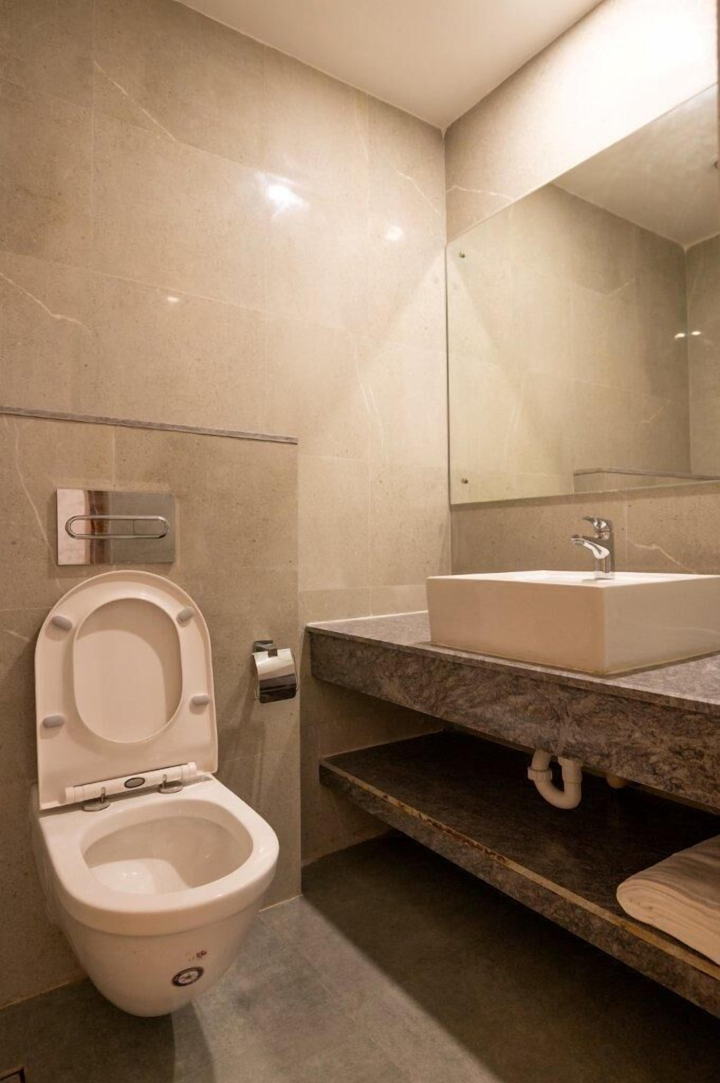 Un baño moderno con inodoro, lavamanos y espejo.