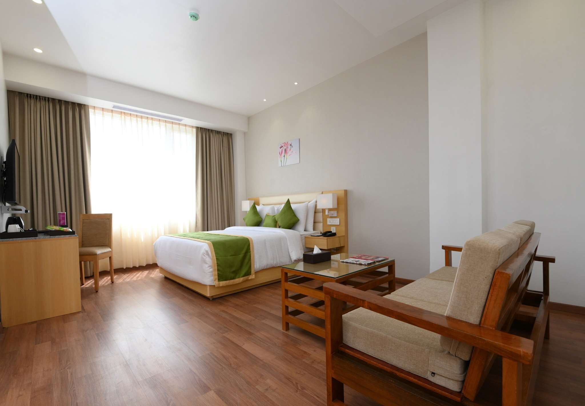 A hotel room with a bed, a sofa, a desk, and a chair.