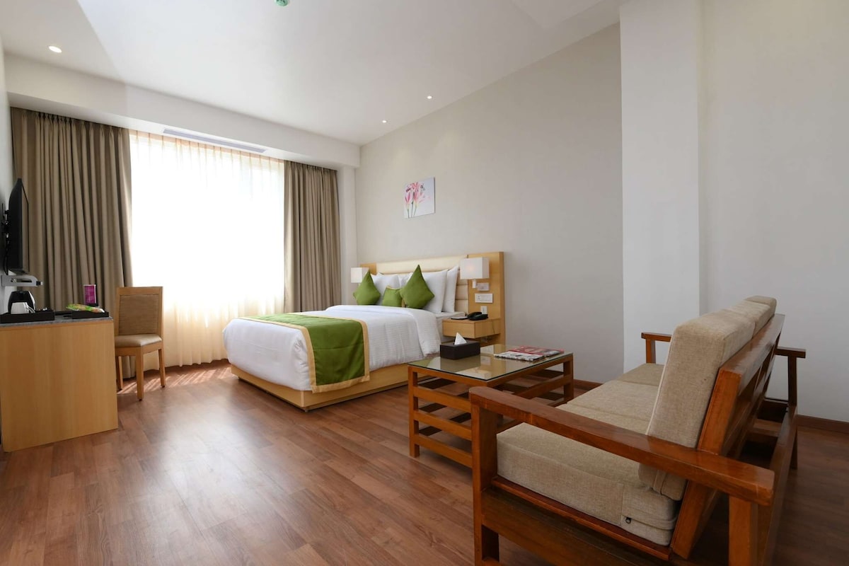 Habitación de hotel con cama, sofá, escritorio y una silla.