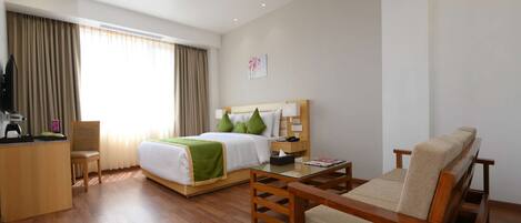 A hotel room with a bed, a sofa, a desk, and a chair.
