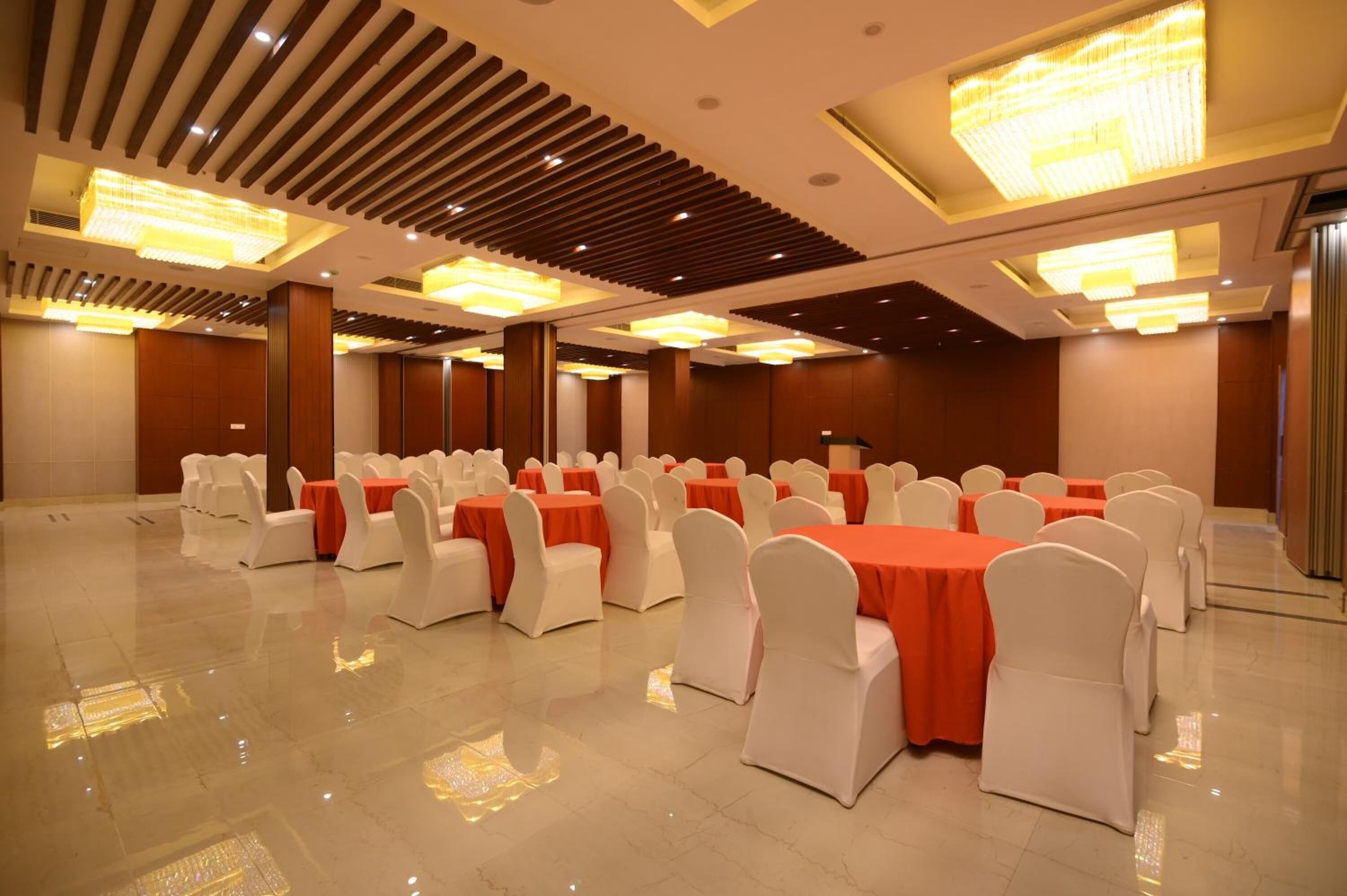 Un amplio salón de banquetes con filas de mesas y sillas, grandes candelabros y un suelo pulido.